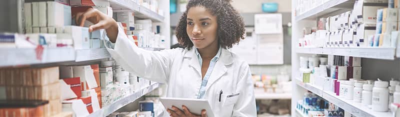 a pharmacist selects an item from the product shelves