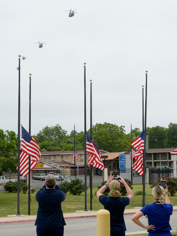 staff at the Central Texas Veterans Health Care System standing near flags at half mast as helicopters approach