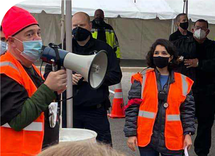 hatton_rdclg - Texas Hospital Association photo of Toby Hatton with a bullhorn and orange vest, speaking to a crowd of masked emergency personnel