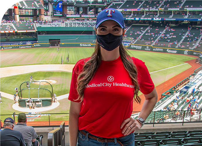 photo of a Sydney Maxwell in the stands of a baseball game, wearing a mask