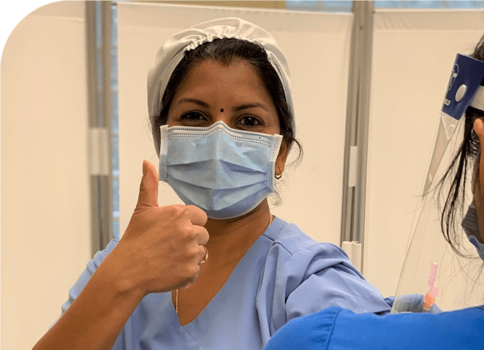 subramanian_rdclg - Texas Hospital Association photo of a Priya Subramanian in a surgical mask and hat, giving the thumbs up sign