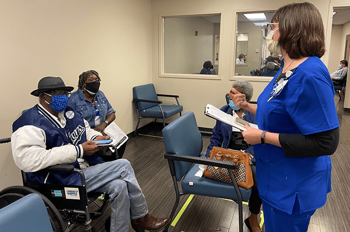 a nurse talking to two people in the THR waiting room