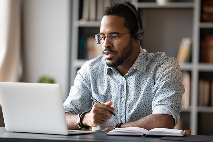 Focused businessman wear headphones study online watching webinar - Texas Hospital Association