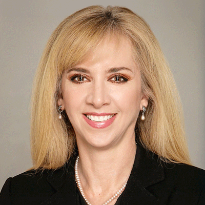 Maria Zampini - Texas Hospital Association Head-and-shoulders portrait of a smiling blonde woman wearing a black blazer and pearl necklace.