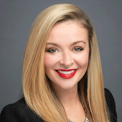 Megan Drake - Texas Hospital Association Professional headshot of a smiling blonde woman in a black blazer against a gray background.