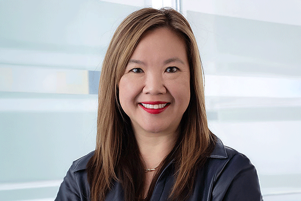 Smiling woman with shoulder-length hair in a navy jacket in a bright, modern office environment