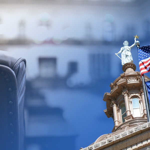 Leather chair in the foreground with a government building and waving US and Texas flags in the background.