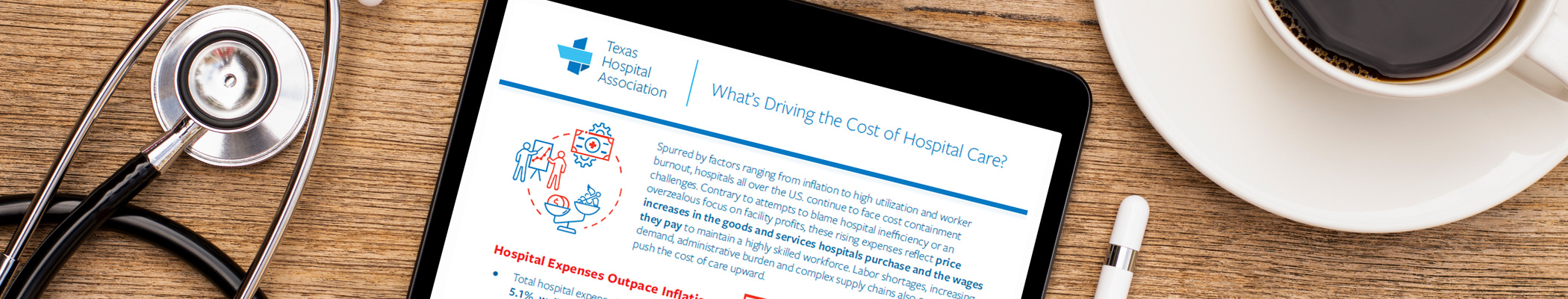 Tablet showing a report titled What's Driving the Cost of Hospital Care? from Texas Hospital Association, on a wooden desk with a stethoscope and coffee cup nearby.