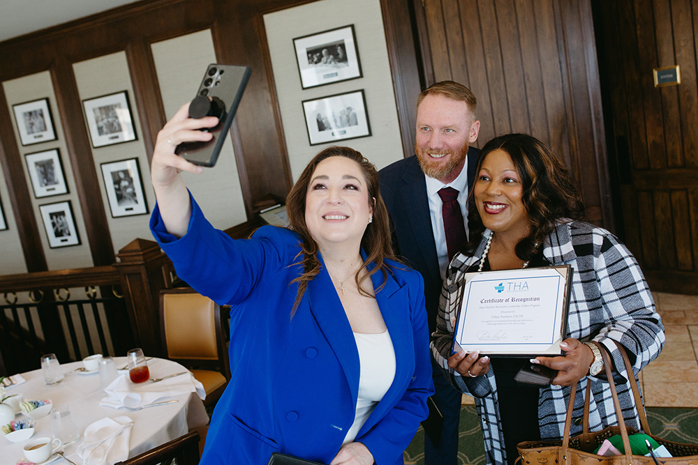 THA Fellows Class of 2026 celebrating their graduation - Texas Hospital Association Woman in a blue blazer takes a selfie with two colleagues; one holds a framed THA certificate.