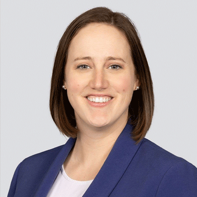 Whitney Babb - Texas Hospital Association Smiling woman with shoulder-length brown hair in a blue blazer against a light gray background.