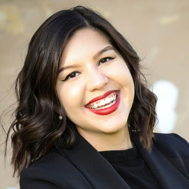 Smiling woman wearing a black blazer, looking at the camera at a professional headshot.