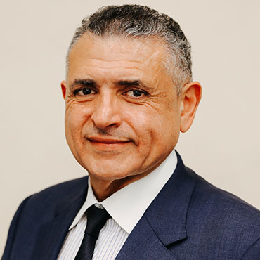 Professional head-and-shoulders portrait of a smiling man in a navy suit and tie.